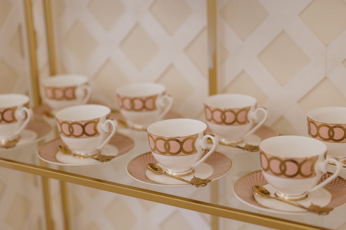 Pink and gold teacups displayed on brass shelves at Monarch Club