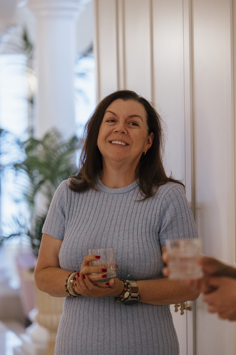 Guest smiling with a drink during arrivals at Tea Time at Monarch