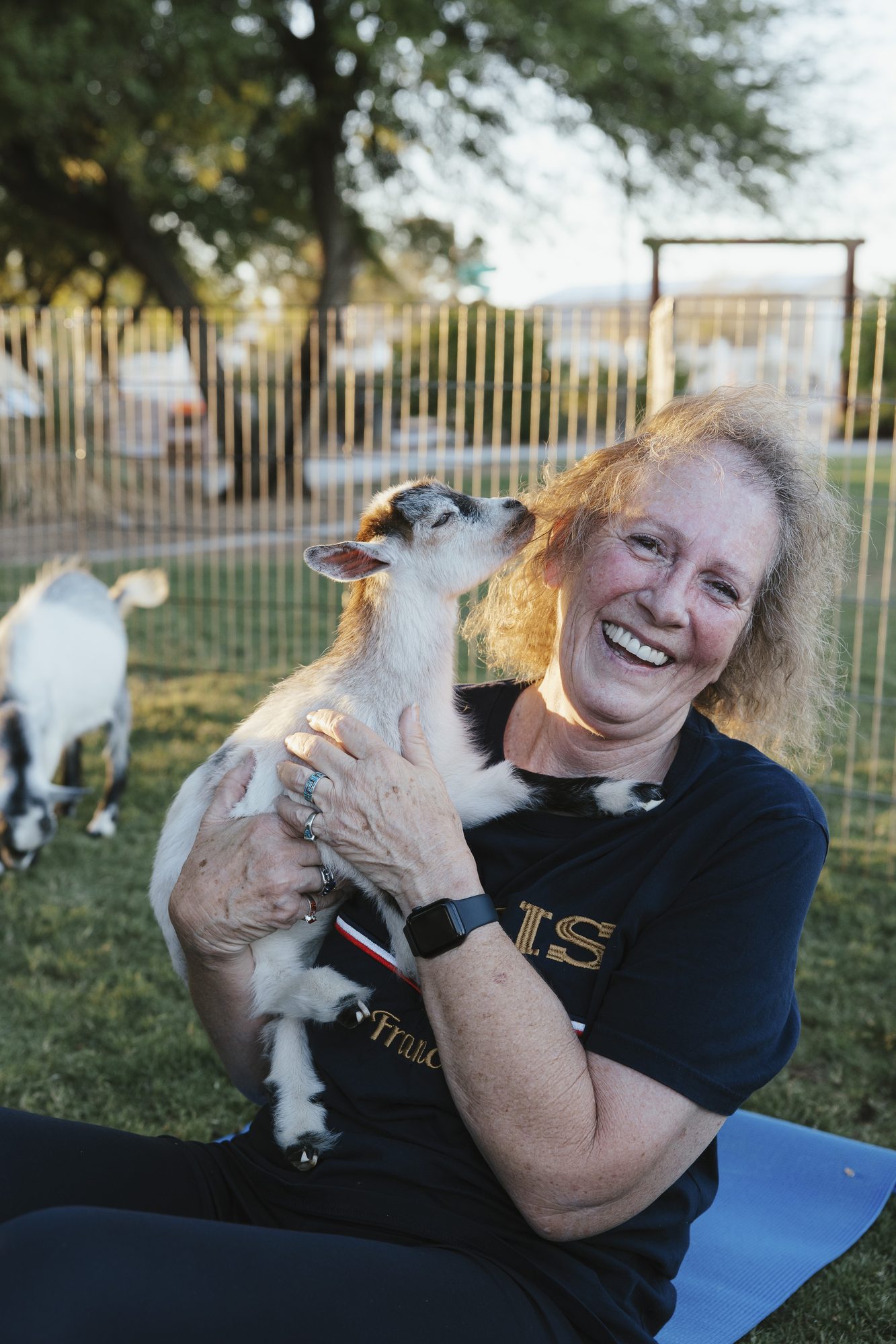 A woman laughs while hugging a goat