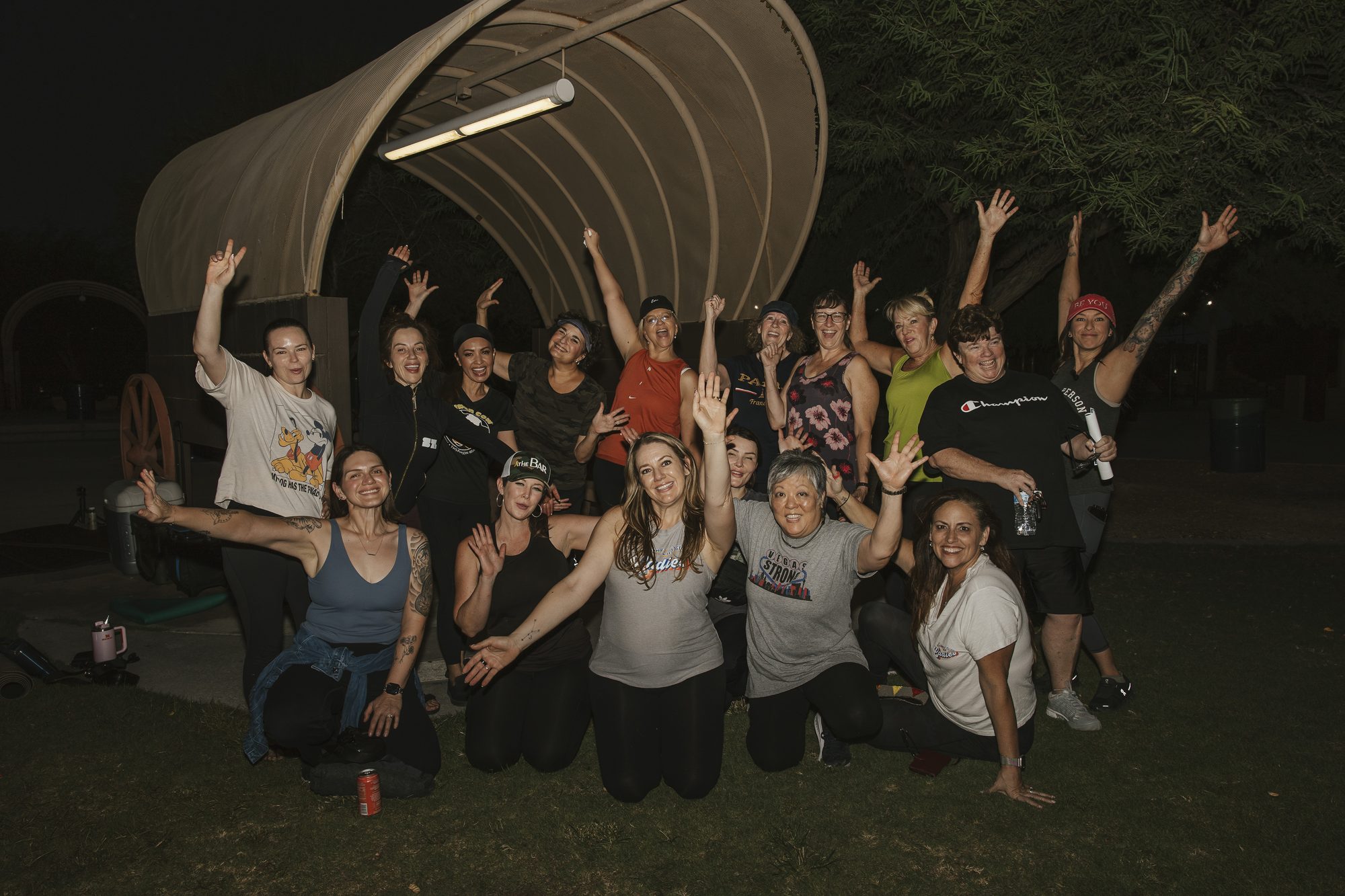 The La Vita Ladies goat yoga group cheers with arms raised at the end of the evening